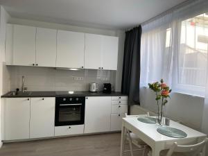 a kitchen with white cabinets and a table with a vase of flowers at Schöne Moderne Wohnung am Ring Nr.1 in Cologne