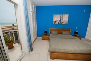 Dormitorio azul con cama y vistas a la playa en Duplex moderne avec vue exceptionnelle sur la mer en Pointe-Noire