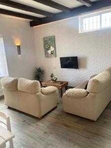 uma sala de estar com 2 sofás e uma televisão de ecrã plano em Casa Puerta sierra de Cádiz em Arcos de la Frontera
