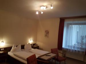ein Hotelzimmer mit einem Bett, einem Tisch und einem Fenster in der Unterkunft Gasthof-Fleischerei Engl in Kötschach