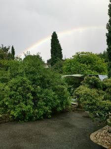 a rainbow in the sky behind trees and bushes at La provence in Saint-Prim +4 photos