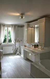 a large white bathroom with a tub and a sink at Maison Hermitage in Aincourt