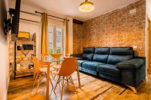 a living room with a black leather couch and a brick wall at Apto céntrico, 2 aparcamientos privados, bicis in Seville