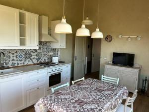 una cucina con tavolo e una cucina con armadietti bianchi di Casa Nonna Ada a Cisterna dʼAsti
