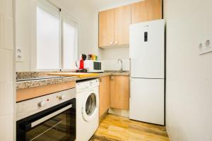 a kitchen with a white refrigerator and a washer at Apto céntrico, 2 aparcamientos privados, bicis in Seville