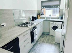 a kitchen with a stove and a washing machine at Coastal Corner in Porthcawl