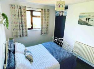 Un dormitorio con una cama azul y una ventana en Coastal Corner, en Porthcawl