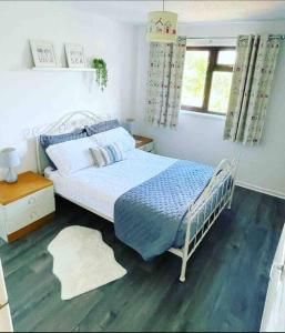 a bedroom with a bed with a blue blanket and a window at Coastal Corner in Porthcawl