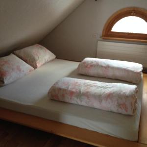a bed with two pillows on it with a window at Ferienhaus Rütiweid in Appenzell