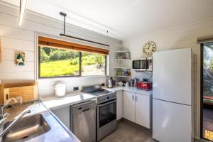 a small kitchen with a refrigerator and a sink at The Bach at Te Toki in Palm Beach