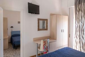 1 dormitorio con cama, escritorio y TV en la pared en Hotel Smart Cervia, en Cervia