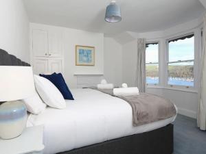 a white bedroom with a large bed and a window at Dartmouth Cottage - River and Sea Views with Parking Permit in Dartmouth