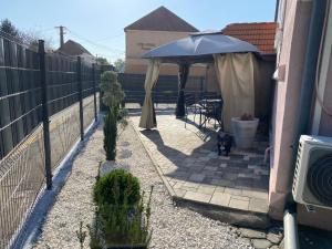 a patio with an umbrella next to a fence at Varkerulet Apartman in Sárvár