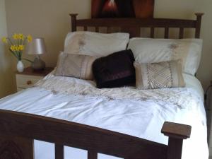 uma cama com lençóis brancos e almofadas em Blossom Hill Bed and Breakfast em Killaloe