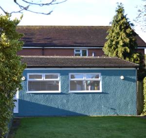 a blue house with two windows and a yard at Greenfield Studio in Cardiff