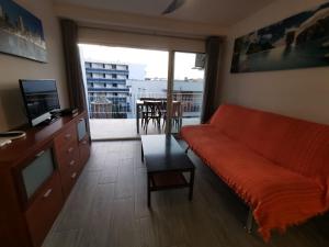 Apartamento céntrico en Salou في سالو: غرفة معيشة مع أريكة برتقالية وشرفة