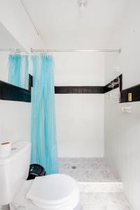 a bathroom with a toilet and a blue shower curtain at Casa de Luz in Cali