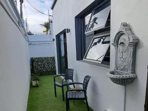 patio z krzesłami i zegarem na boku domu w obiekcie Cosy Carlisle w mieście Port Elizabeth