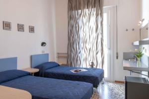 Habitación de hotel con 2 camas y ventana en Hotel Smart Cervia, en Cervia