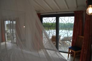 Habitación con cortina blanca y ventana en +221 Lagune Beach House, en Mbodiène