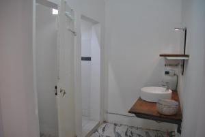 Baño blanco con lavabo y espejo en +221 Lagune Beach House, en Mbodiène