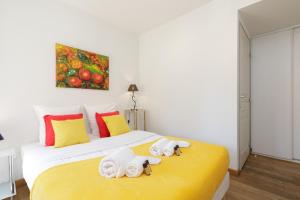 ein Schlafzimmer mit einem gelben Bett mit Handtüchern darauf in der Unterkunft Greg YourHostHelper in Cannes