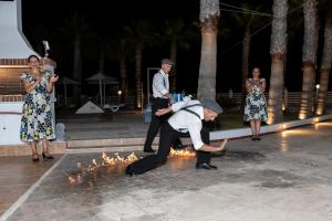 a man and a woman are standing around a fire at Mammis Beach Hotel in Kardamaina