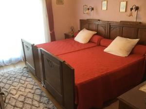een slaapkamer met een groot bed met rode lakens en witte kussens bij Maison individuelle dans les Vosges du nord in Niederbronn-les-Bains