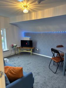 sala de estar con TV, mesa y sillas en Quirky Attic Blackpool, en Blackpool