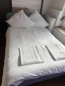 uma cama branca com lençóis e almofadas brancos em SleepWell100 em Colônia