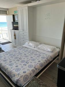 a small bedroom with a bed and a kitchen at OB Oceanfront Studio - closest to the beach in Ormond Beach