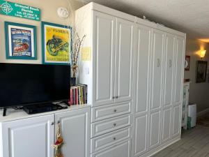 a living room with white cabinets and a flat screen tv at OB Oceanfront Studio - closest to the beach in Ormond Beach