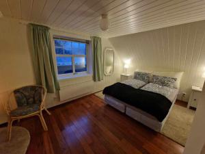 een slaapkamer met een bed, een stoel en een raam bij Dragon Villa Reine in Reine