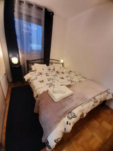 a bedroom with a bed with a blanket and a window at Apartment Relax with infrared Sunshower in Varaždin