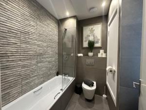 a bathroom with a bath tub and a toilet at The Cardiff Apartment in Cardiff