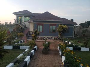 dom z ogrodem z kwiatami przed nim w obiekcie Alice Gardens and Campsite w mieście Entebbe