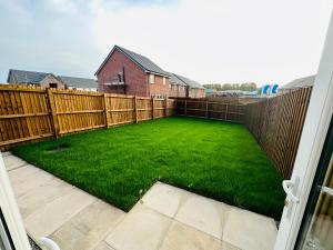 a backyard with a fence and a green lawn at Newhaven House in Liverpool