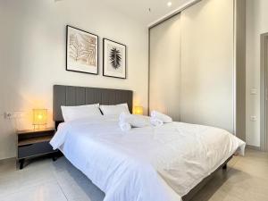 a bedroom with a large white bed with two towels on it at Chic Getaway Near Stavros Niarchos in Athens