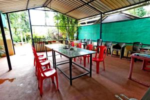 a restaurant with red chairs and a table and tables and chairs at Karadikallu Homestay - Private Waterfalls & Guided Trek in Sakleshpur