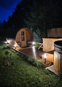 a round wooden cabin with lights in a yard at night at Domki trzy jeziora z zewnętrznym SPA - sauna, balia do schładzania i jacuzzi in Małe Swornigacie