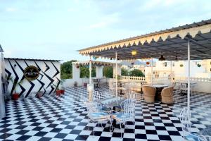 a patio with tables and chairs on a checkered floor at Hotel Tree of heaven in Udaipur