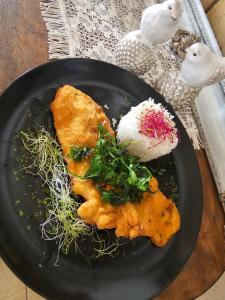 a black plate with food on a table at Vánkos & Eszcájg in Újhartyán +15 photos