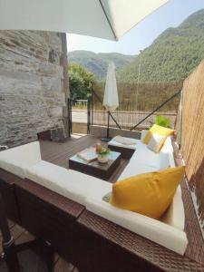 een witte bank op een balkon met een tafel en een parasol bij La Escondida in Caboalles de Abajo