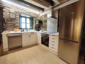 uma cozinha com armários brancos e um frigorífico de aço inoxidável em La Escondida em Caboalles de Abajo