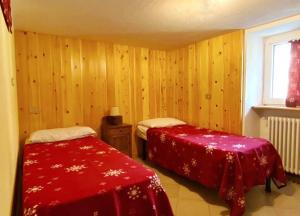 a bedroom with two beds with red covers and a window at APPARTAMENTO CON GIARDINO in Crépin