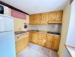 a small kitchen with wooden cabinets and a refrigerator at APPARTAMENTO CON GIARDINO in Crépin