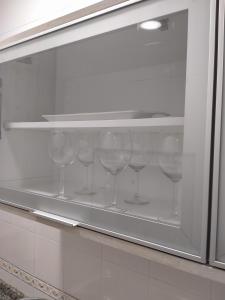 een rij wijnglazen op een plank in een keuken bij Apartamento las tres lunas in Sanlúcar de Barrameda