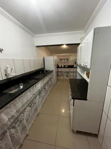 - une cuisine avec des appareils électroménagers blancs et des comptoirs noirs dans l'établissement Casa de Irene, à Cabo Frio