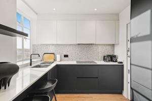 uma cozinha com armários a preto e branco e um lavatório em Luxury Kensington Flat with Terrace and AC em Londres