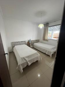um quarto branco com 2 camas e uma janela em Casa de Irene em Cabo Frio